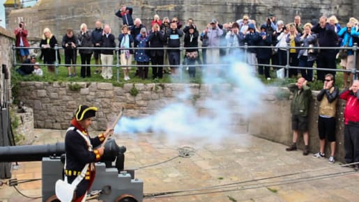 A man in uniform fires a cannon