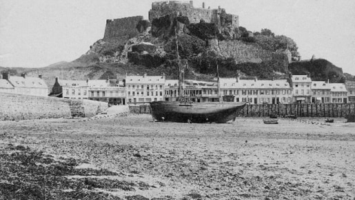 Black and white photo of a castle, a bay and a boat.