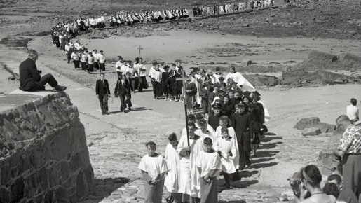 A group of people take a Pilgrimage across a causeway