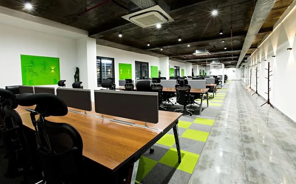 Open-plan workstations with acoustic ceiling and green accent walls in a 42,000 sq ft back office in Udyog Vihar, Gurgaon
