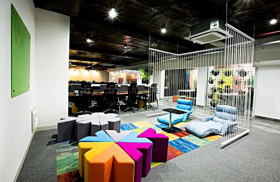 Breakout lounge with colourful modular seating and a timber slat feature in a Gurgaon office
