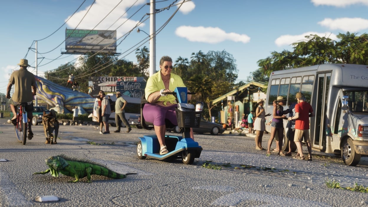 Official Grand Theft Auto VI trailer still of Leonida street life — a woman on a mobility scooter, an iguana on the asphalt, and a tourist shuttle under palm trees