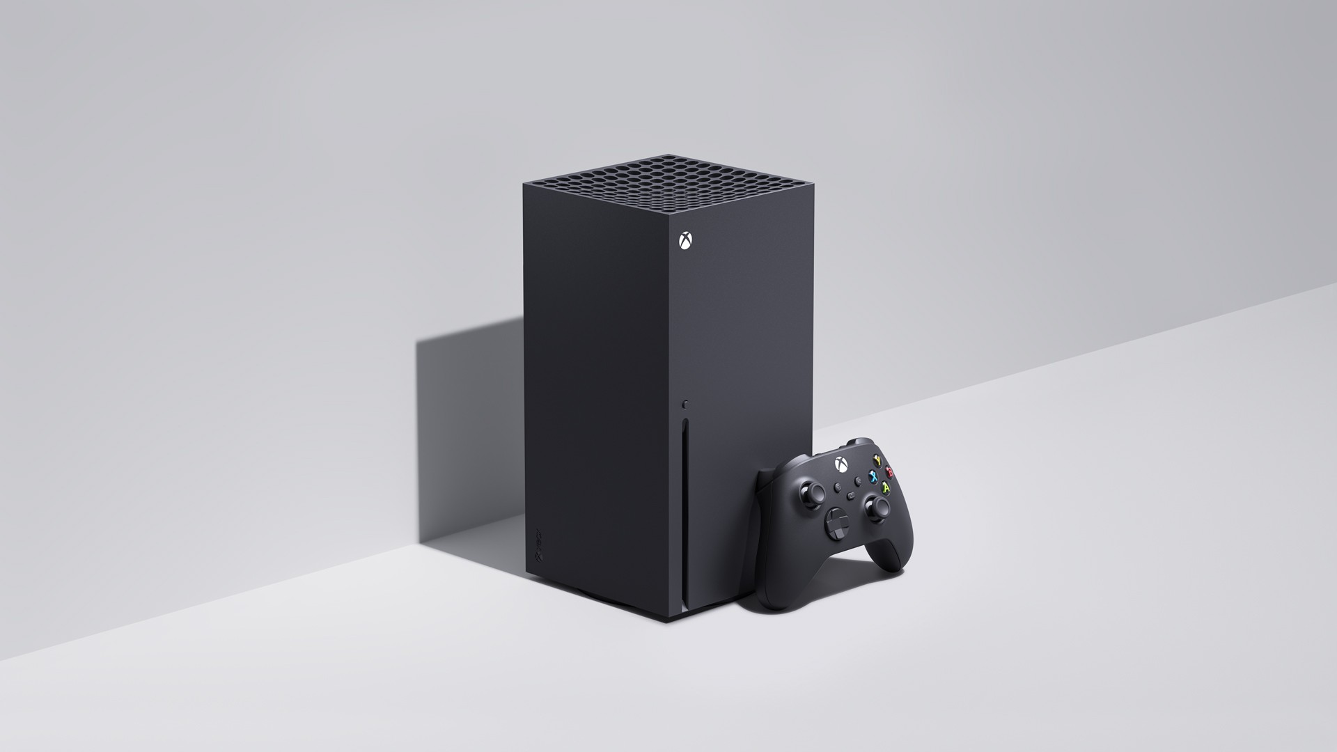 Black Xbox Series X console standing upright next to a black Xbox Wireless Controller on a light grey background