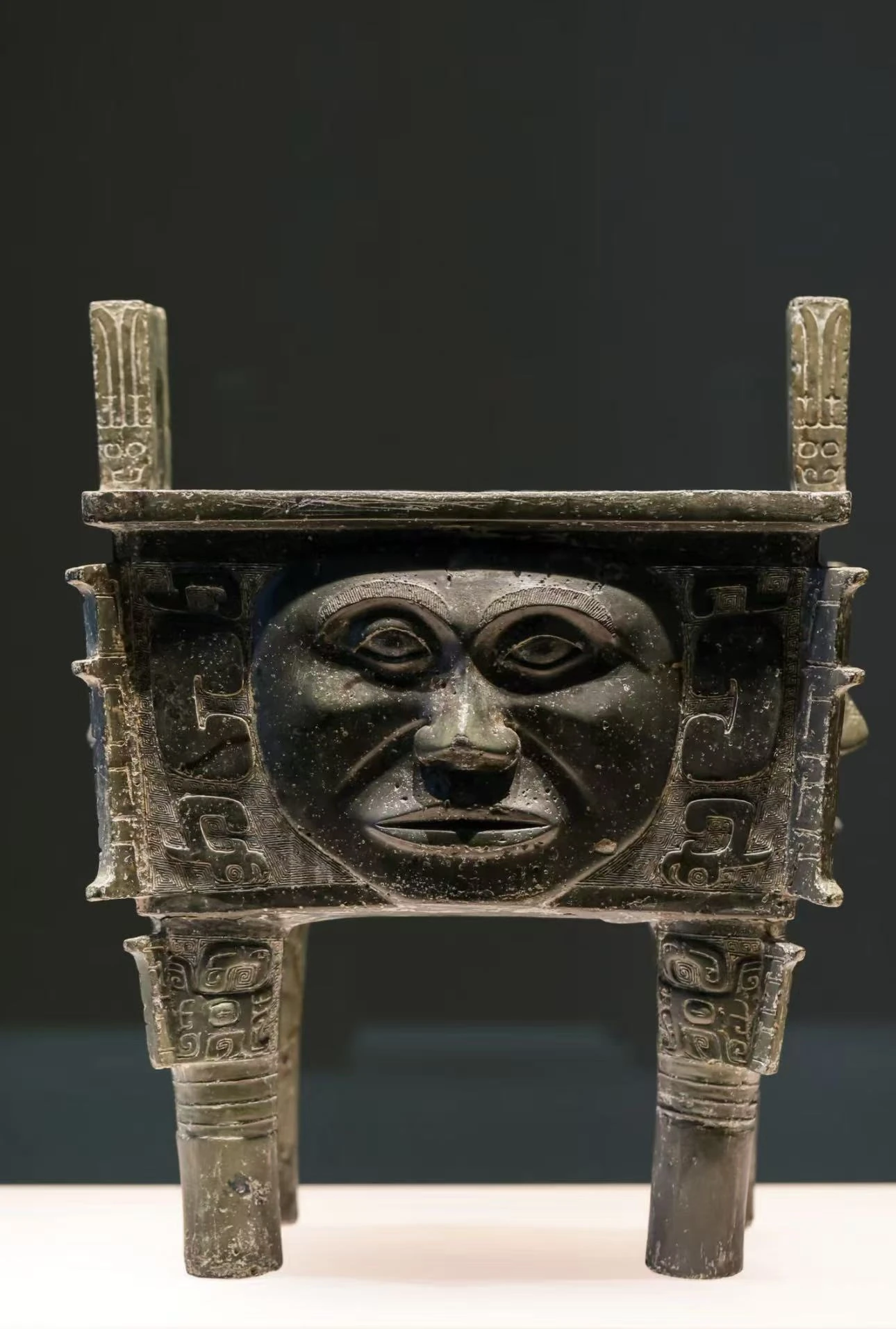 Square bronze ding with a sculpted face