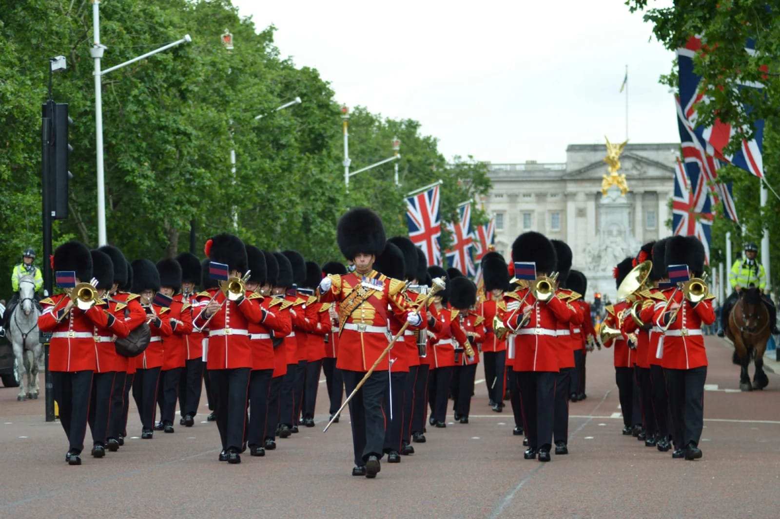 Banda militar de los Foot Guards con túnicas escarlata y gorros de piel marchando por The Mall hacia el Palacio de Buckingham durante el cambio de guardia