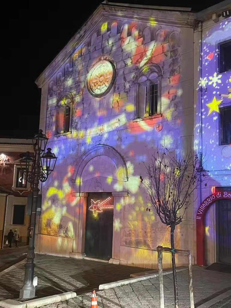 Colorful projection mapping washing a stone church facade at night — Infinity Projectors