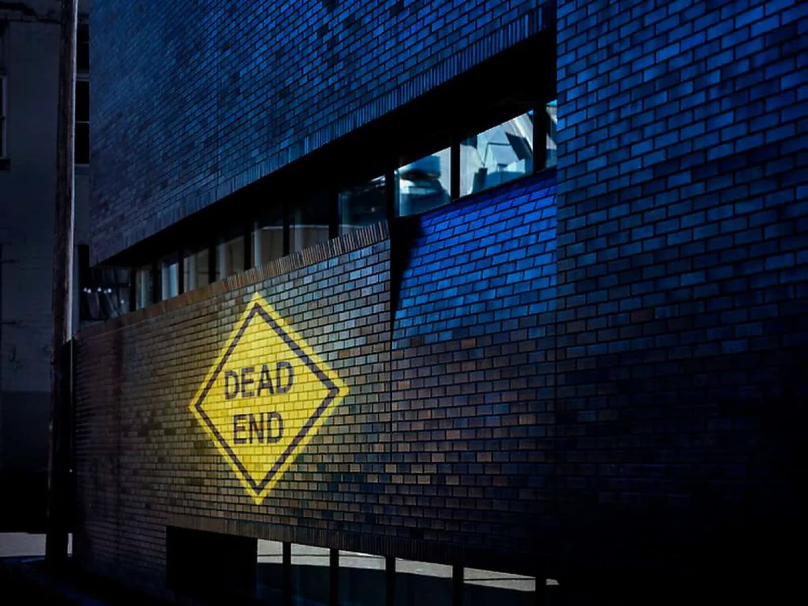 Infinity Projectors logo projected on a brick wall along a city street at night — outdoor gobo projector