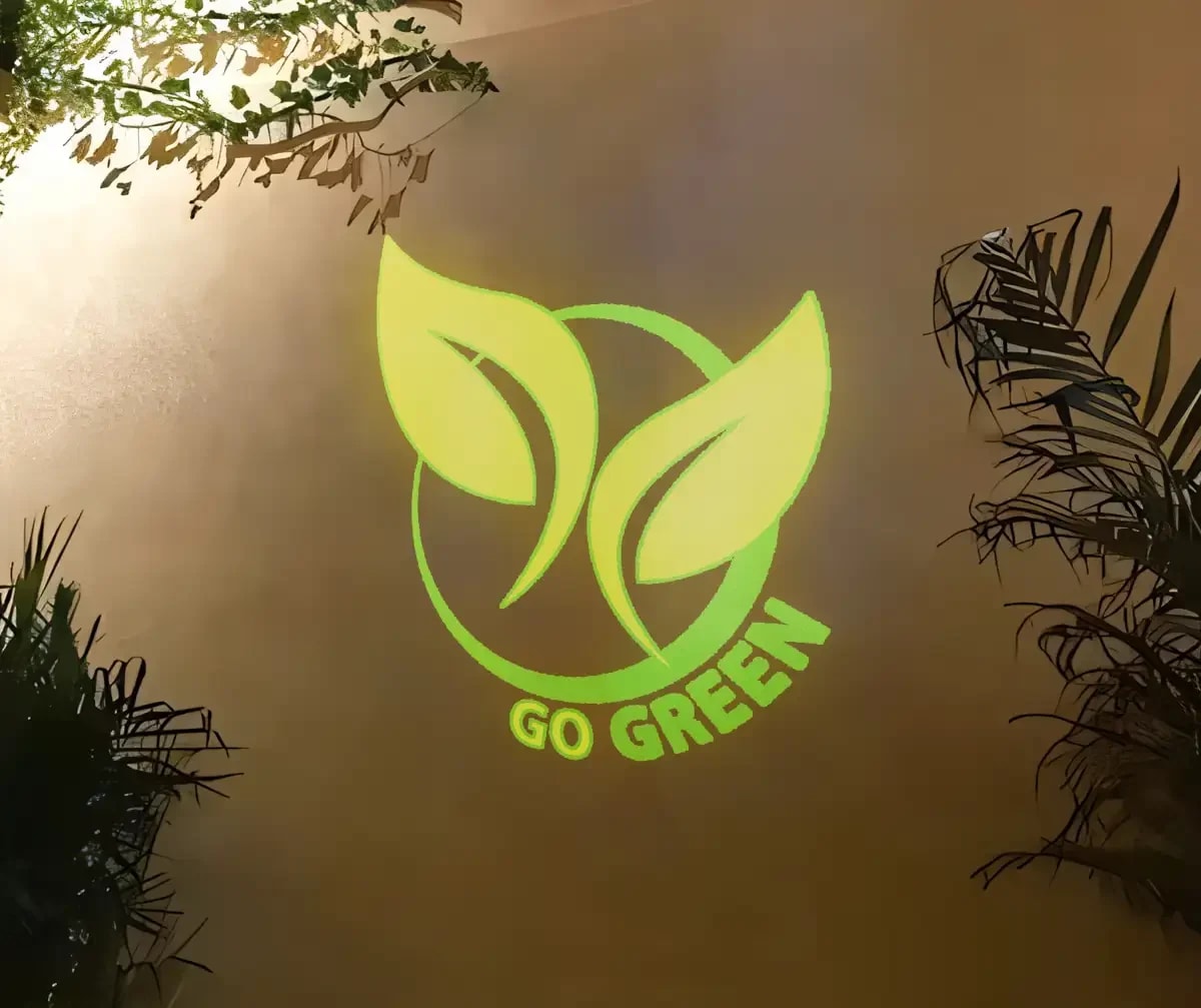 Go Green leaf logo glowing yellow-green on a warm indoor wall framed by plants, cast with a custom gobo