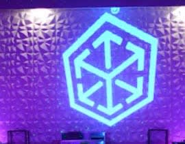 Video: blue geometric cube-and-arrows emblem projected large on a textured ballroom wall