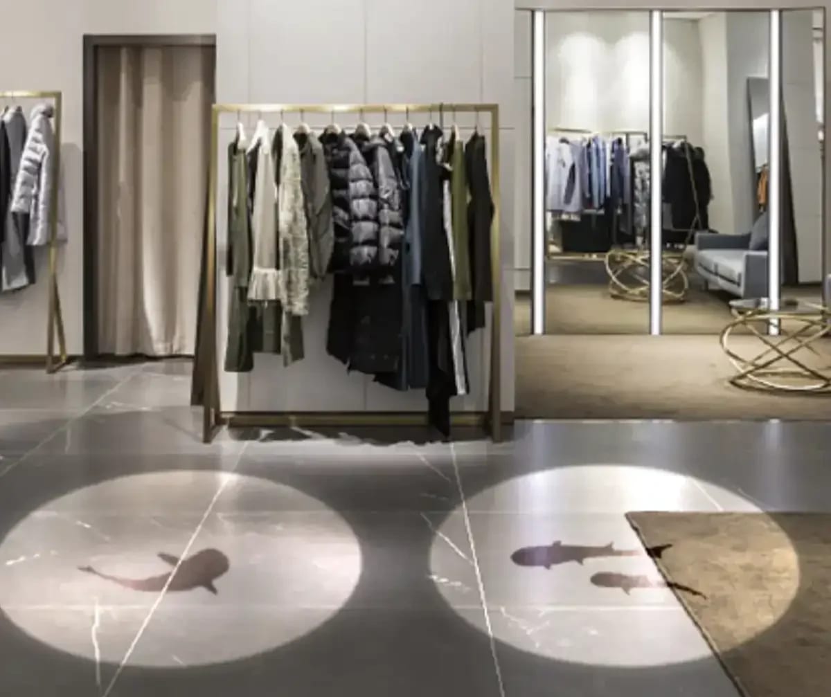 Twin spotlight circles with koi silhouettes on a clothing boutique's marble floor from small gobo projectors