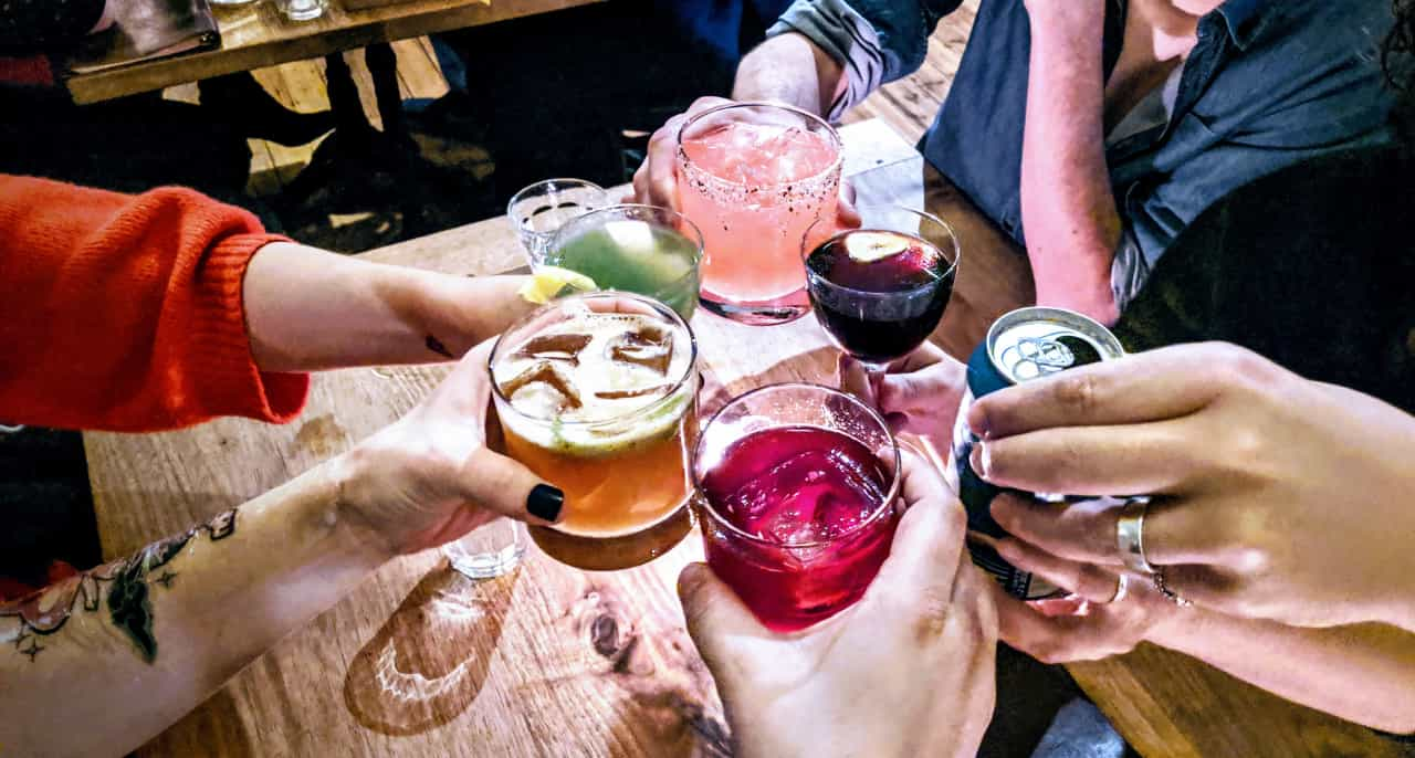 Six drinks raised in the middle of tables in a toast.