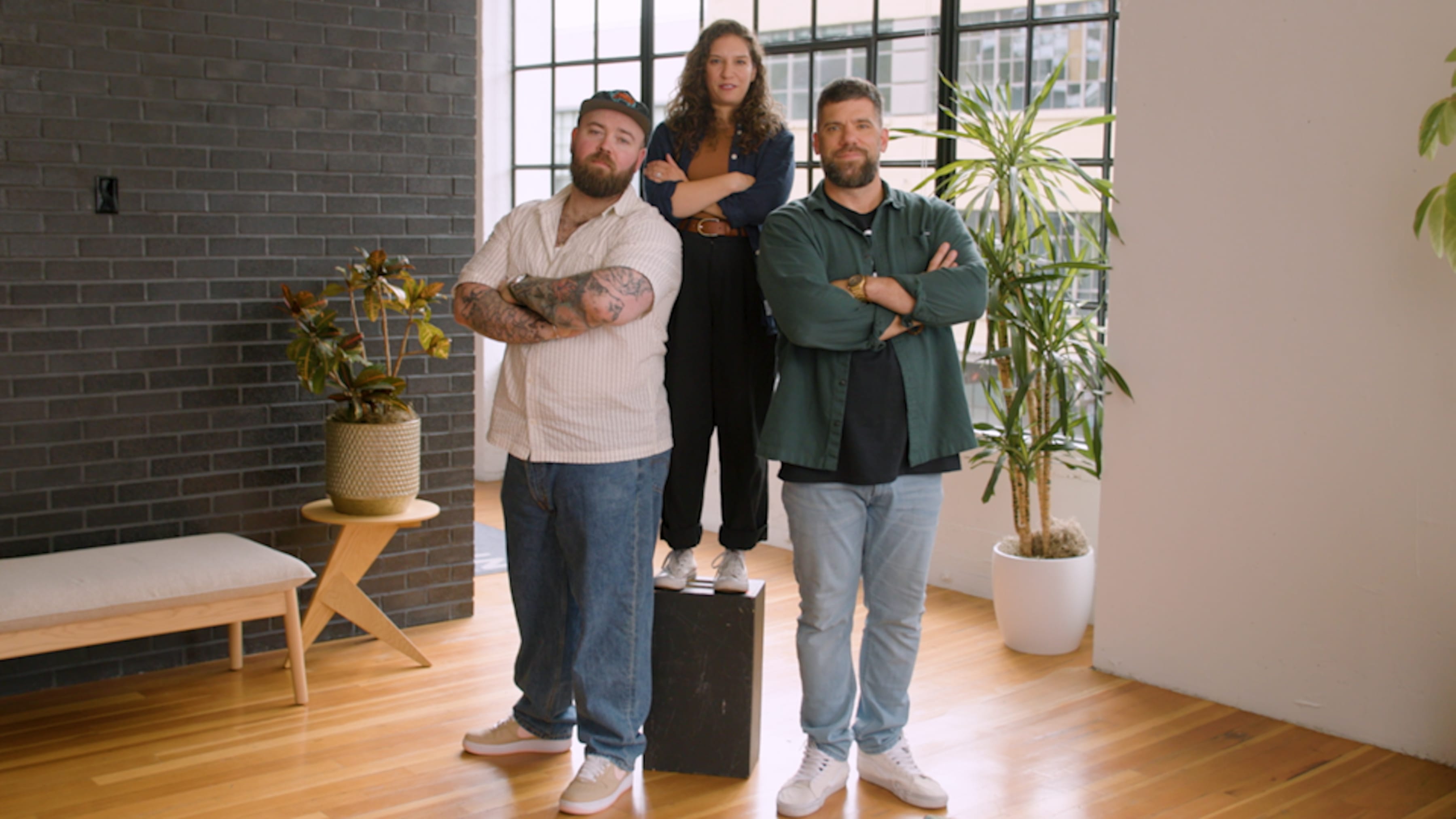 three people standing together with their arms crossed, looking confidently into the camera