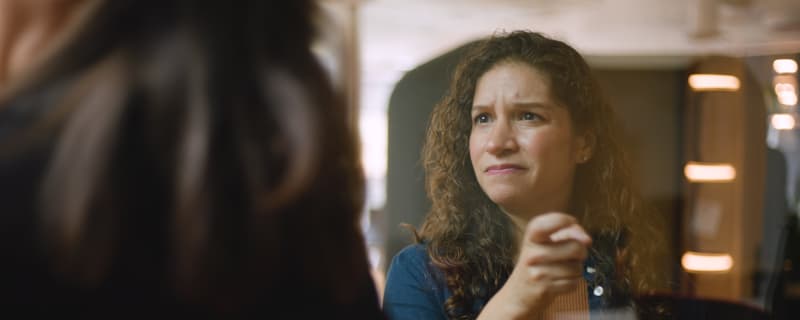 a woman knocking on glass with a quizzical look on her face
