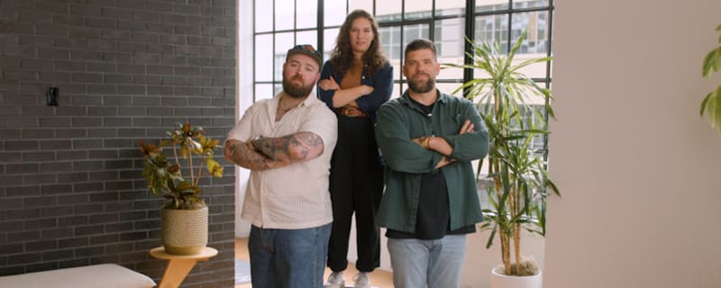 three people standing together with their arms crossed, looking confidently into the camera