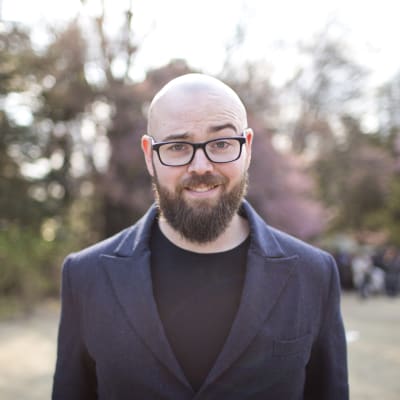 Jason Lengstorf smiling and raising an eyebrow in a park.