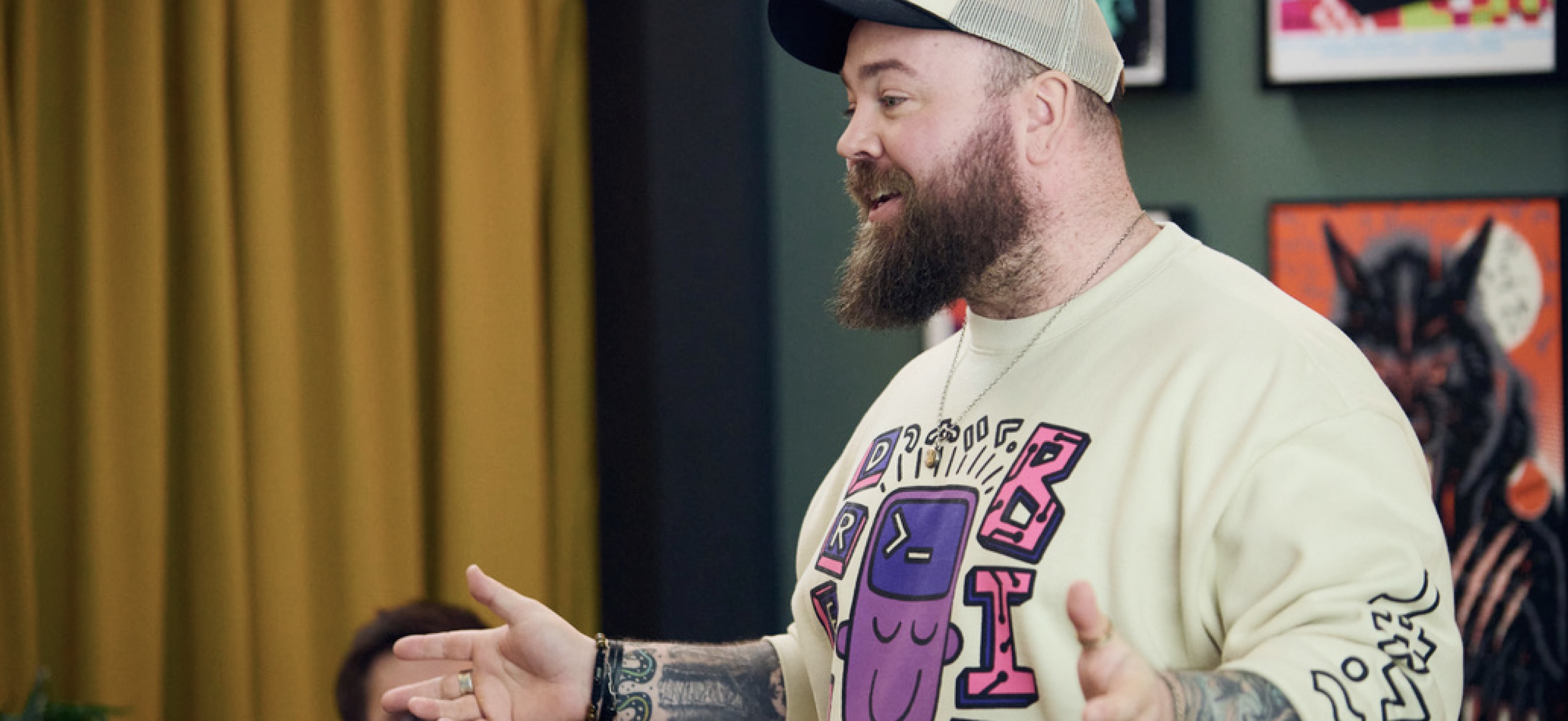 Jason standing in front of the Web Dev Challenge lounge with a big smile and outstretched hands