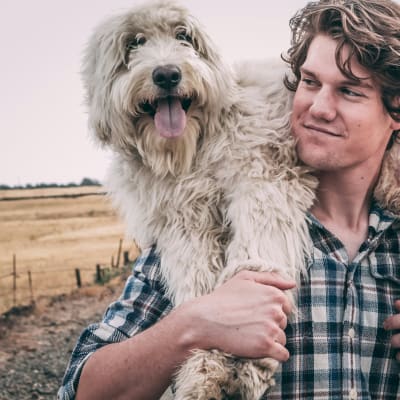 man carrying long-coated white dog