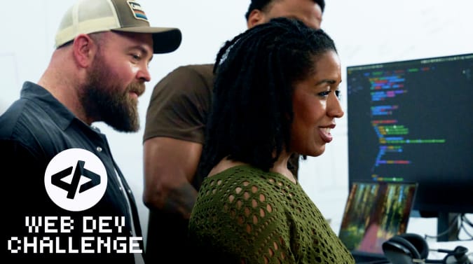 A group of people looking at a monitor together. There's another monitor with code on it visible in the background. The Web Dev Challenge logo is in the lower left corner.