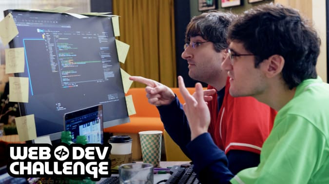 Michael and Miles looking at a monitor displaying code. there are sticky notes all around the monitor in a chaotic fashion