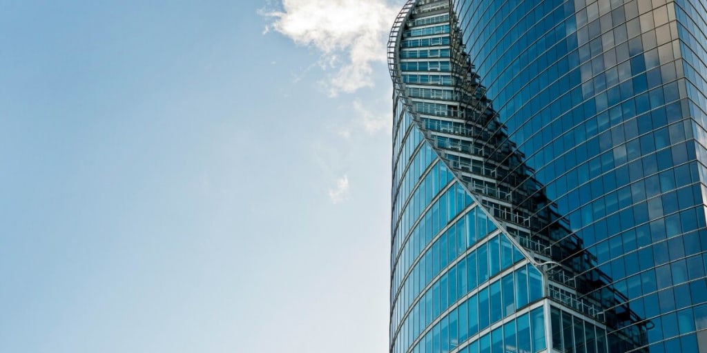 Unique glass office building with blue sky and clouds