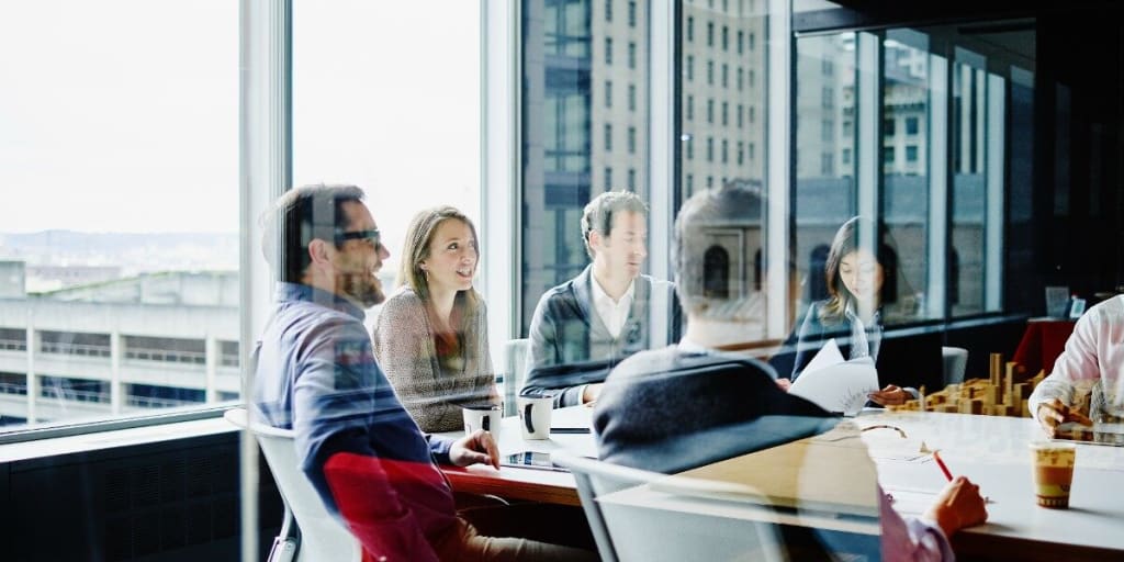 Business men and women meet around a conference table in a high-rise conference room