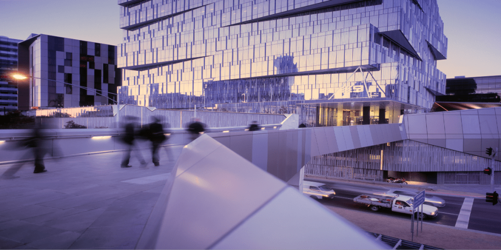 Business people walking across bridge to modern office building