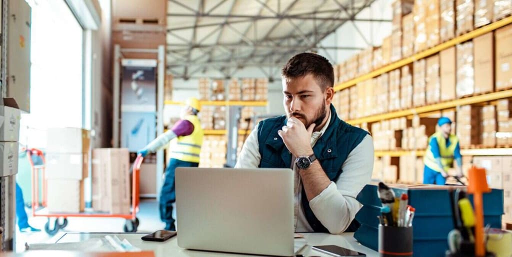 Facilities manager with laptop in warehouse