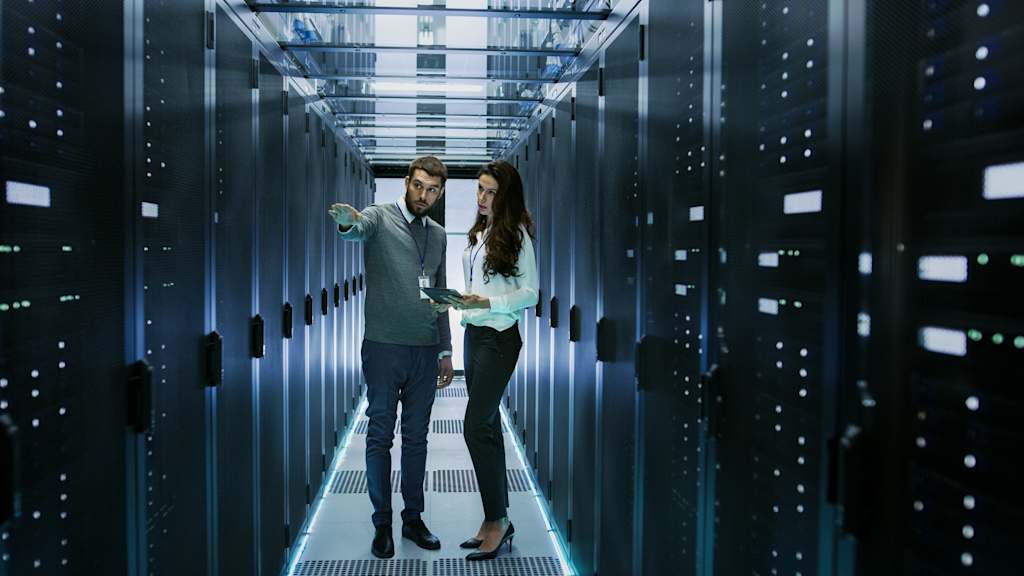 It engineer shows working data center server room to female chief engineer who holds tablet computer | jllt