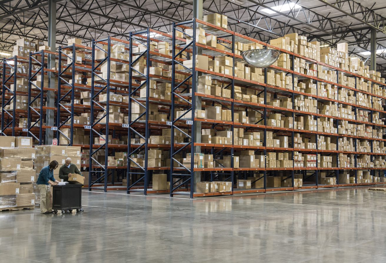 two-employees-checking-inventory-beside-racks-of-boxes-in-temporary-storage-in-a-distribution-warehouse two-employees-checking-inventory-beside-racks-of-boxes-in-temporary-storage-in-a-distribution-warehouse