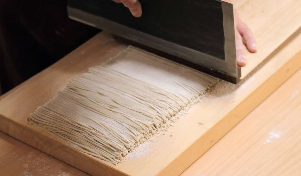 Making soba noodles and cutting them in strings