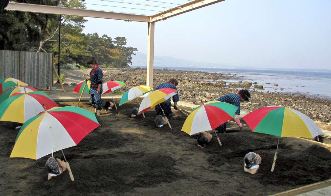 a group of women lie buried on beach under umbrellas