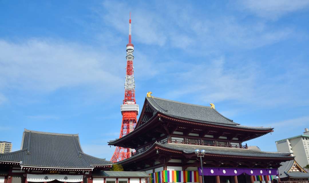 A temple roof with a red and white tower behind it