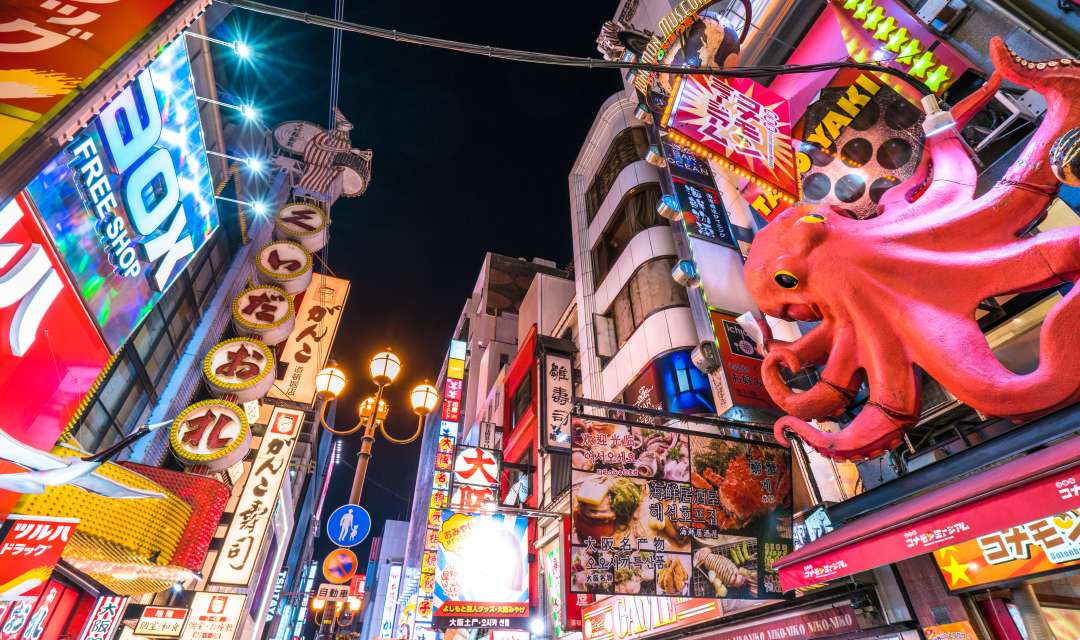 a street at night with neon signs and an octopus model