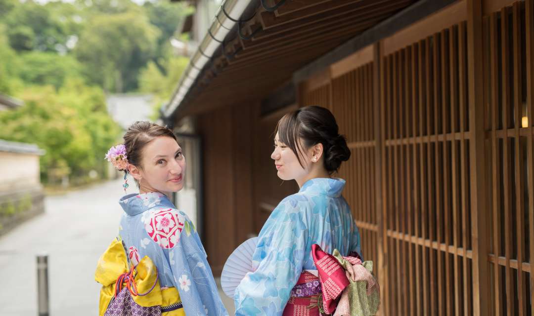 two women in yukata smiling at each other