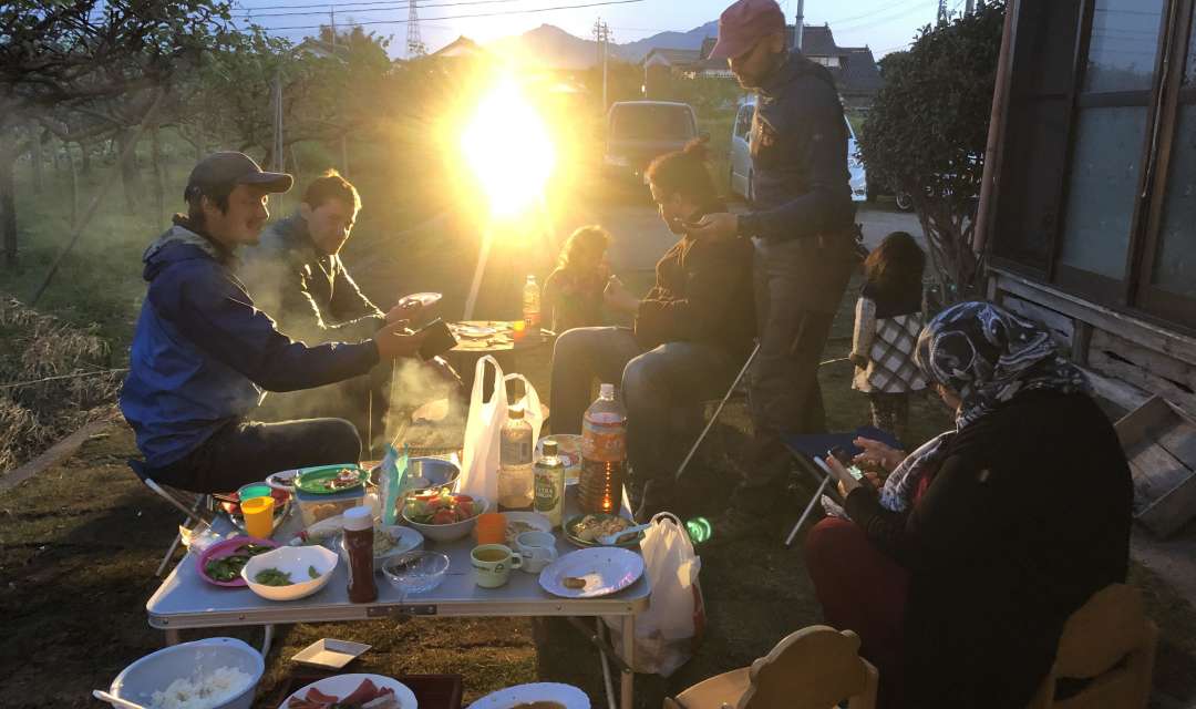 A group of people eat simple food as the sun sets