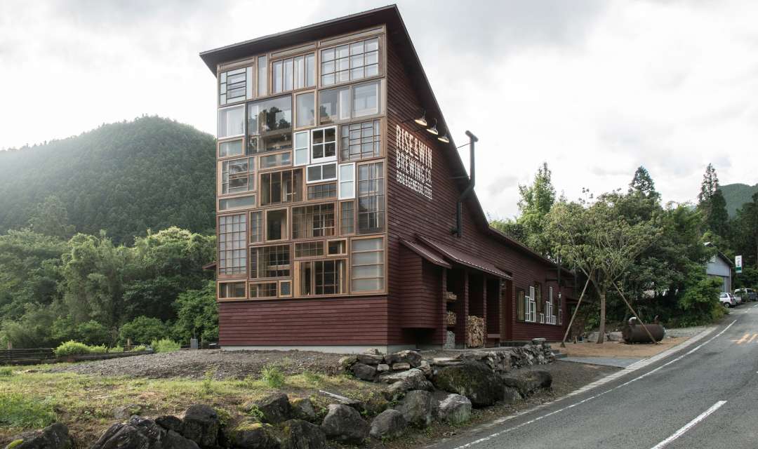 A wooden and glass building surrounded by mountains and nature