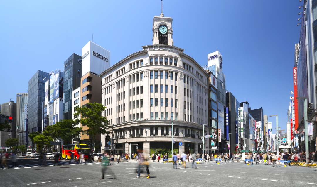 A city street in front of a large building with a clock on the top