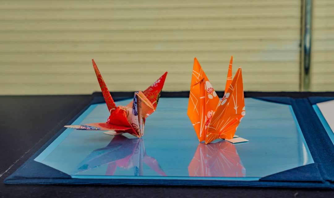 two colorful folded paper birds on a table