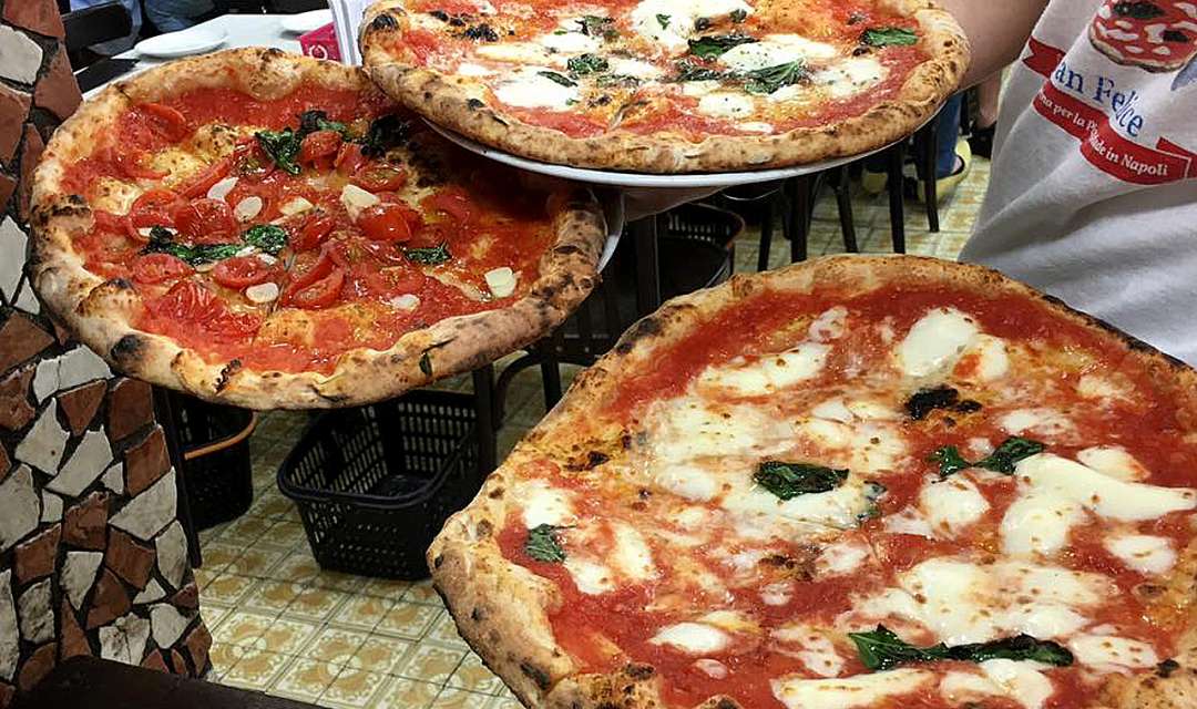 three pizzas on plates held by waiter