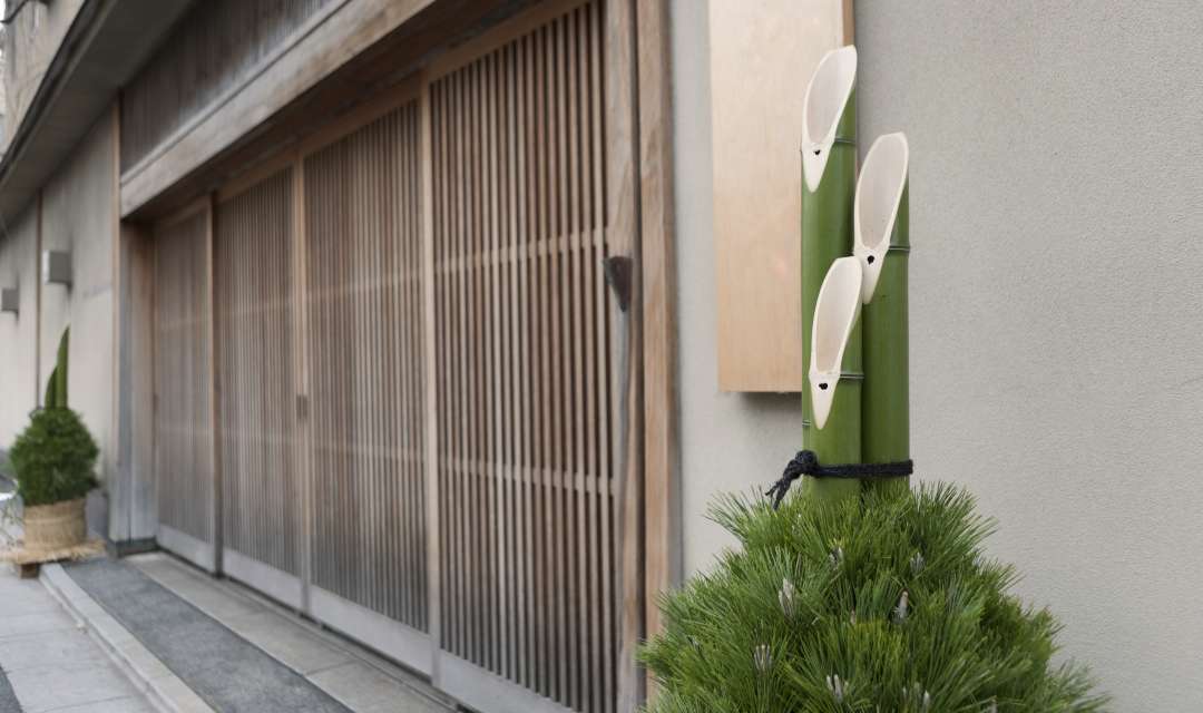 three pieces of green bamboo standing upright in front of a wooden door