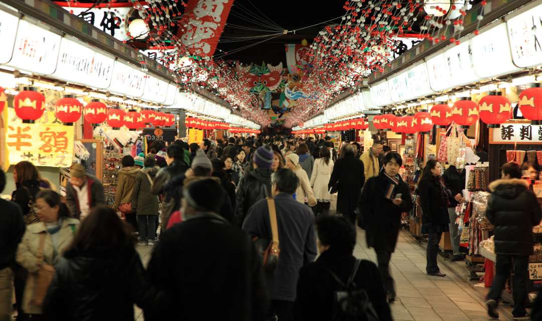 a path lined with shops full of people shopping at night