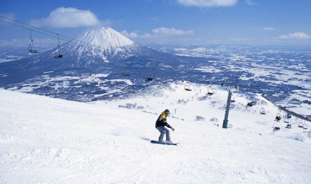 a person skiing with a ski lift and snowy mountain in the background