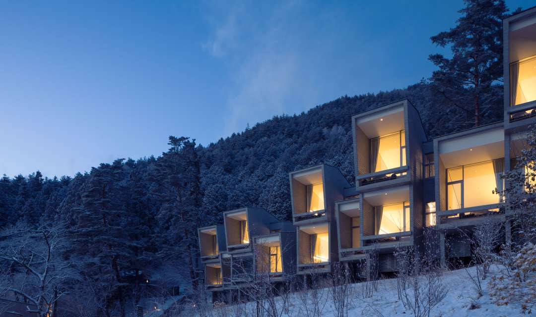 stacked square lit-up cabins on a snowy mountainside at night