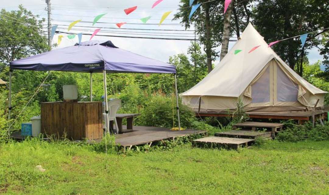 a small shelter and a tipi in a grass field