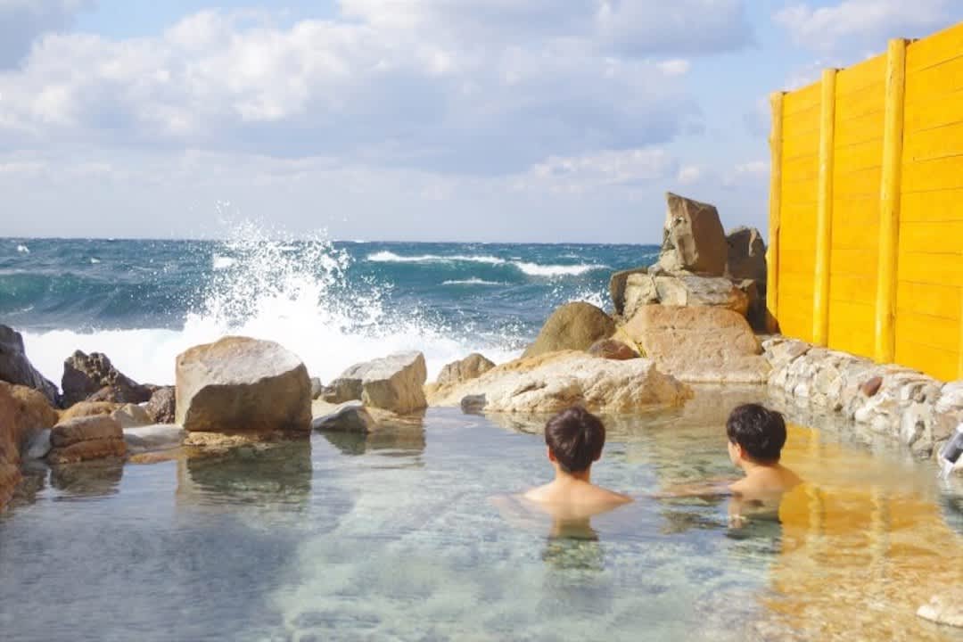 Saki-no-Yu onsen with waves crashing in front of bathers.