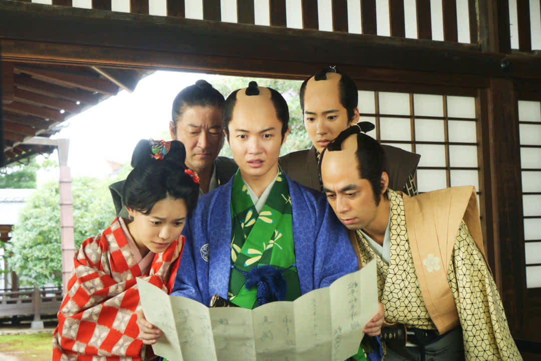 Promotional image for the film We’re Broke, My Lord!, with 5 people wearing traditional Japanese clothes and looking at a paper inside a traditional Japanese house