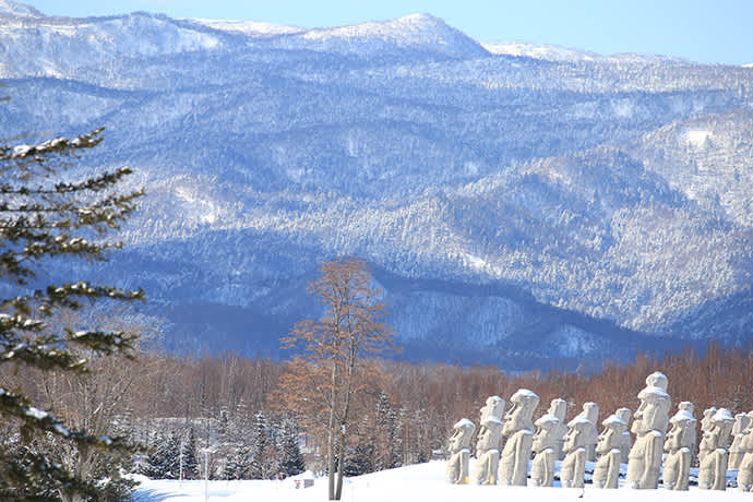 Snow covers the Moai statues and surrounding mountains in winter. Photo credit: Makomanai Takino Cemetery