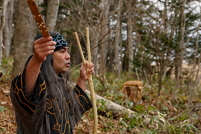 Ainu guide Kengo Takiguchi holds a ritual offering stick (ikupasuy) in his right hand.