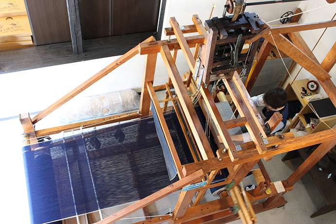 A Momotaro artisan at work on the customized denim weaving loom Photo credit: Japan Blue Co., Ltd.