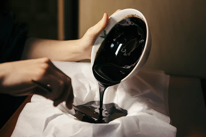 Gleaming, jet-black Joboji lacquer being filtered. Photo credit: Ninohe City